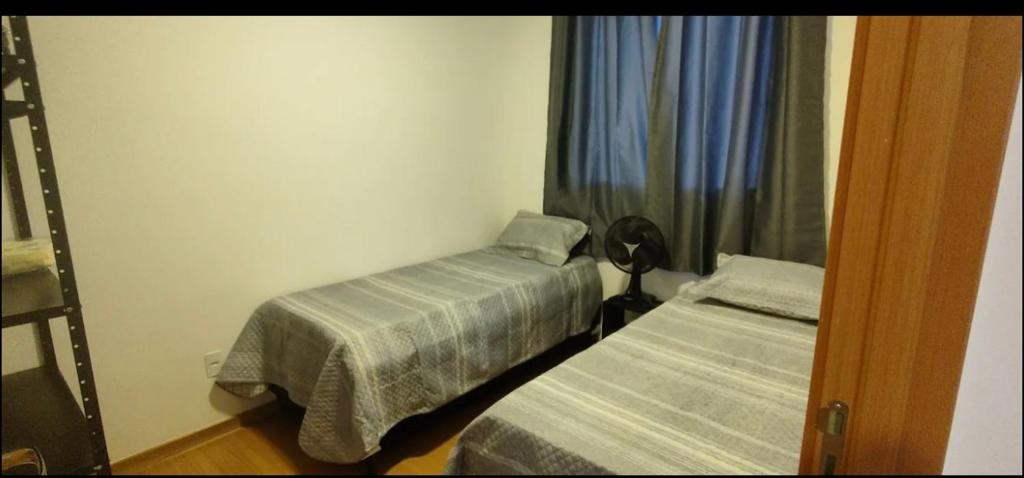 a small room with two beds and a window at Apartamento Incrivel in Campo Grande