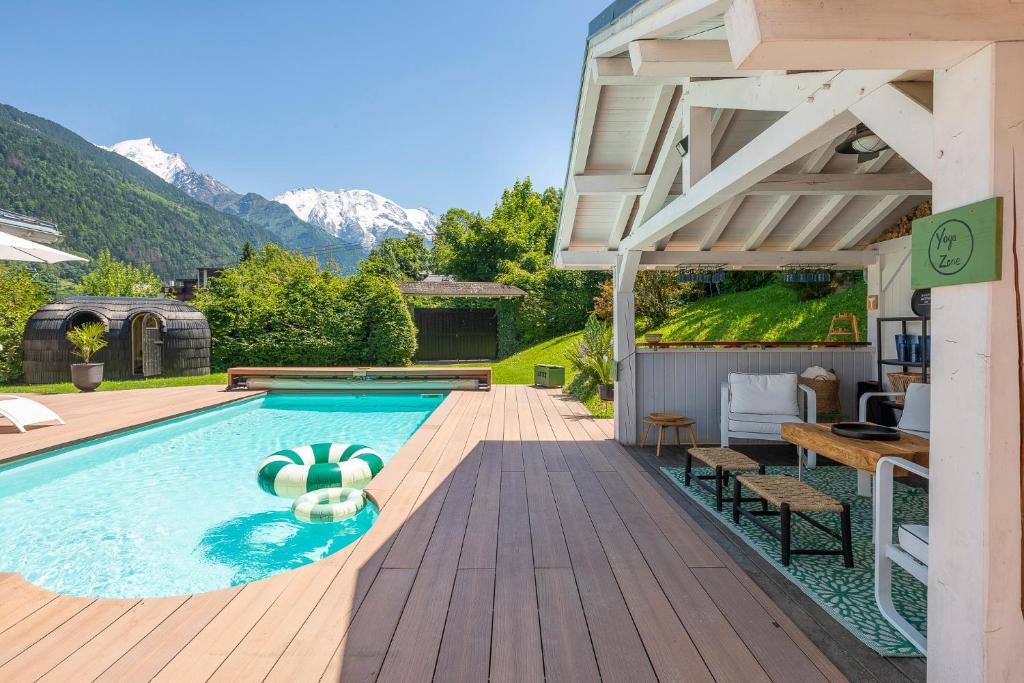 una piscina con terraza de madera y una casa en Chalet Soleil Blanc en Saint-Gervais-les-Bains