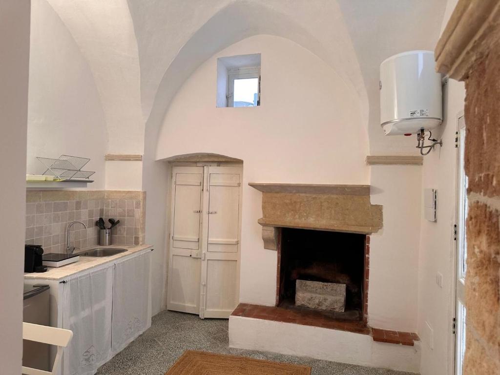 een keuken met een open haard en een wastafel bij Dimora Lucrezia - A in Corigliano dʼOtranto