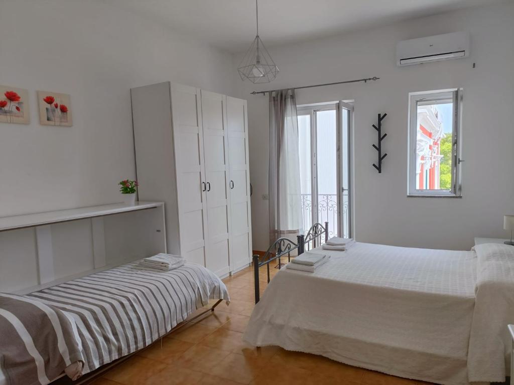 a white bedroom with two beds and a window at A Casicedda in Lipari