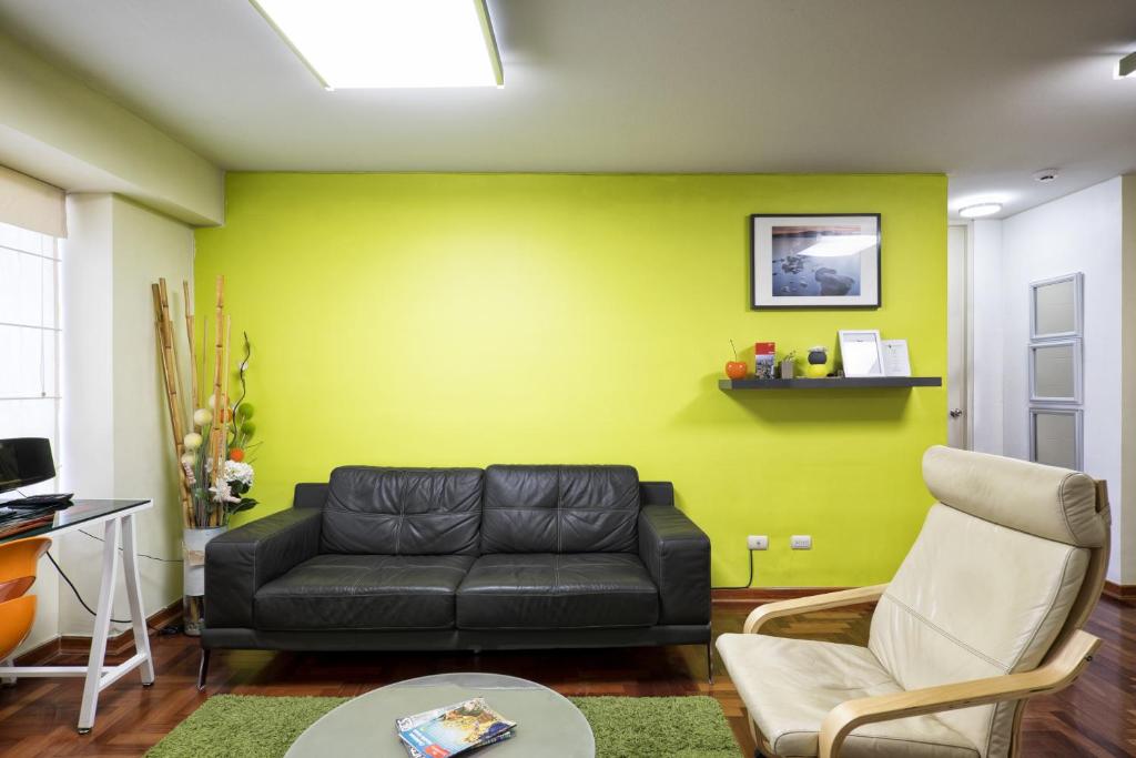 salon z czarną kanapą i żółtą ścianą w obiekcie La Masia Apartments w mieście Lima