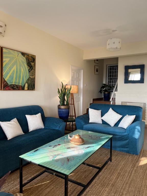 Sunset Villa في كونور: غرفة معيشة مع أرائك زرقاء وطاولة زجاجية