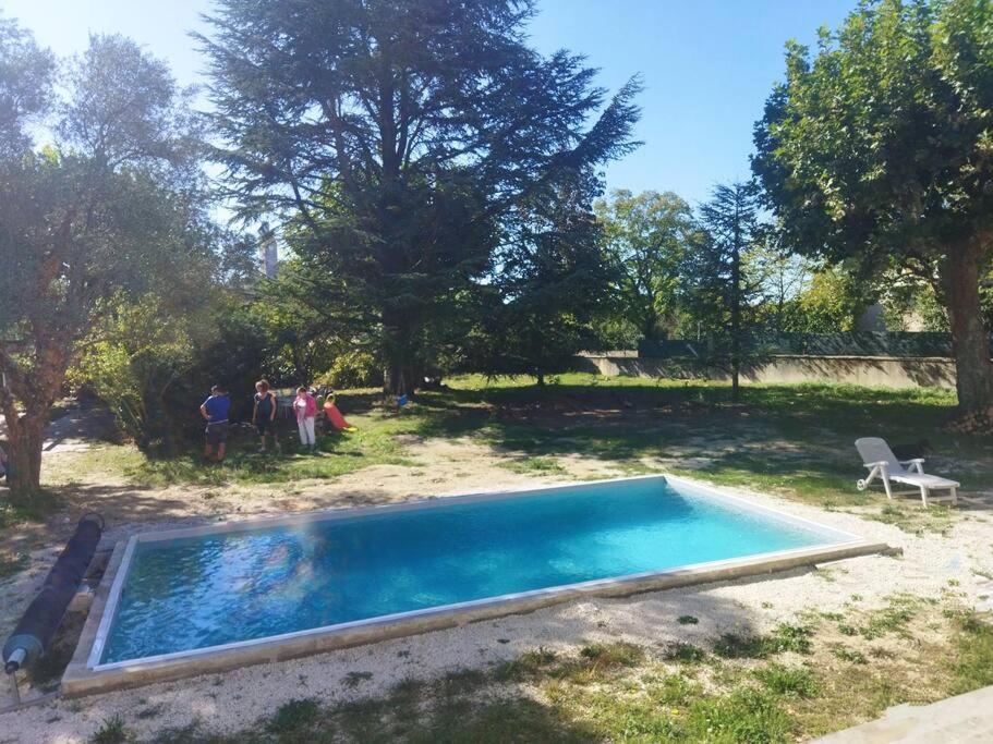 ein Schwimmbad in einem Hof mit herumstehenden Menschen in der Unterkunft la Villa Charme et Confort in Chamaret