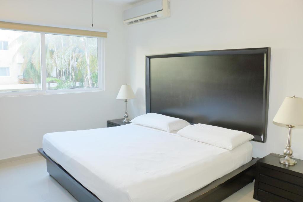 - une chambre blanche avec un grand lit et une fenêtre dans l'établissement Luxury Coral Dream, à Playa del Carmen