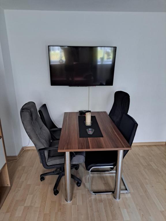 a table with chairs and a tv on a wall at 2 Raum Zwickau Privat in Zwickau