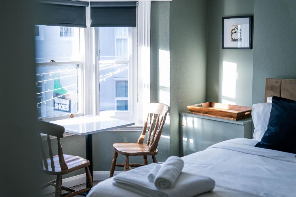 1 Schlafzimmer mit einem Bett, 2 Stühlen und einem Fenster in der Unterkunft Sunshine in the Laines in Brighton & Hove