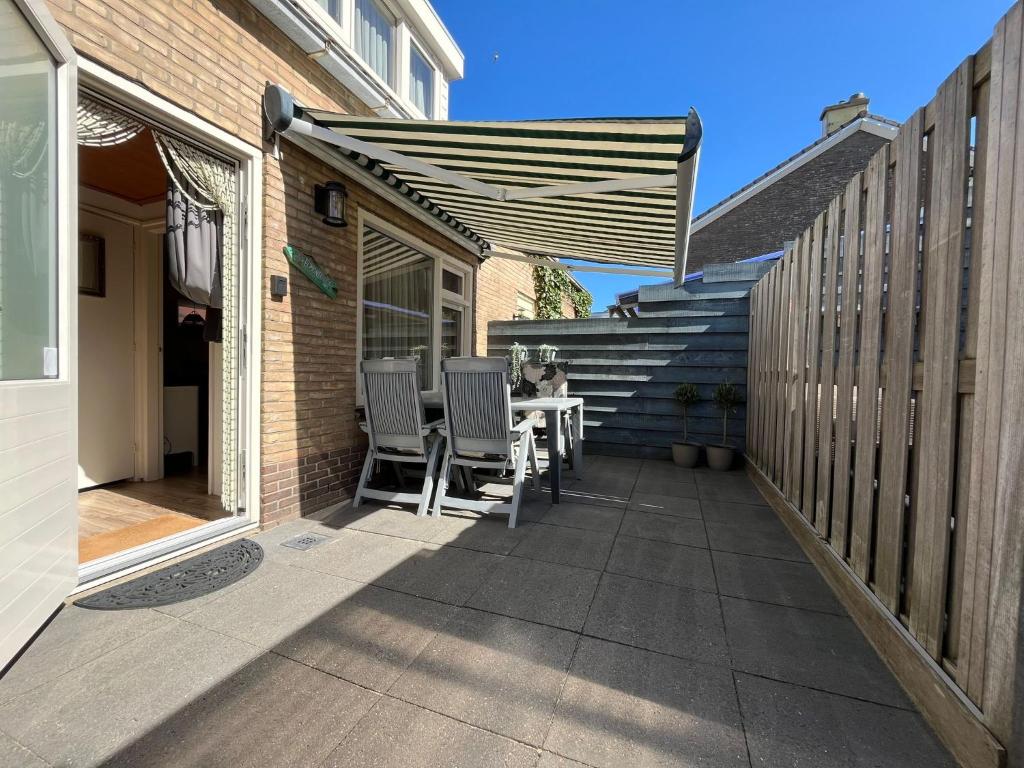 een patio met een tafel, stoelen en een trap bij Zomerhuis Beach EnJoy in Egmond aan Zee