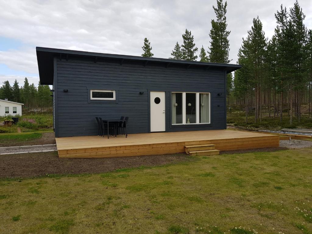 une petite maison noire avec une terrasse en bois dans l'établissement Gäststuga, nära Piteå havsbad., à Piteå