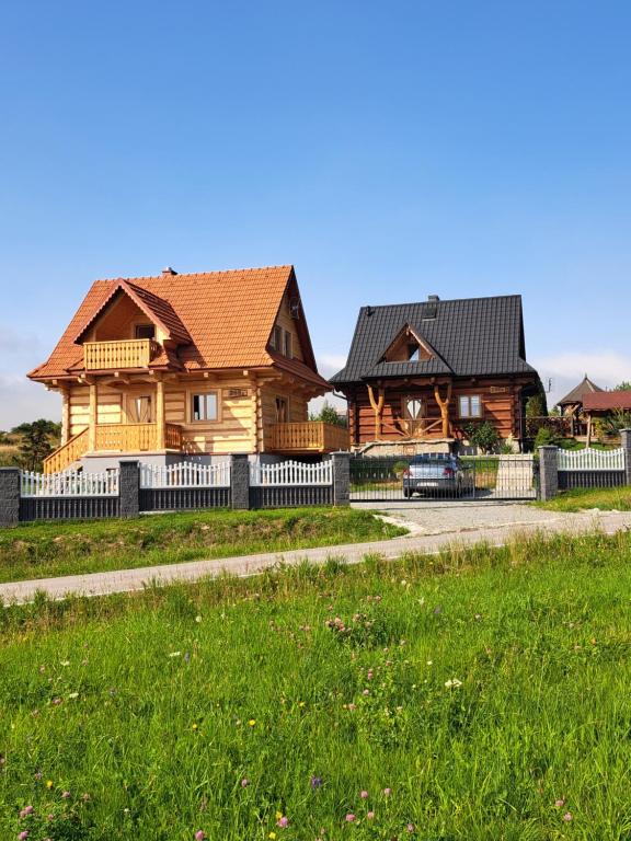 a wooden house with a fence and a grass field at Domki na Wzgórzu in Piekielnik