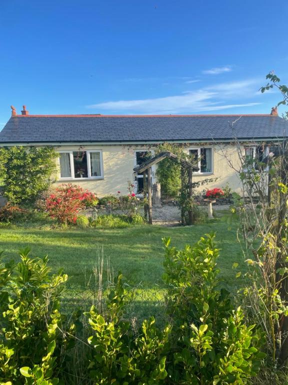 a house with a lawn in front of it at Honeycomb Cottage - a quiet, charming, cosy retreat in the countryside only 2 miles from one of Cornwall's best beaches in Truro