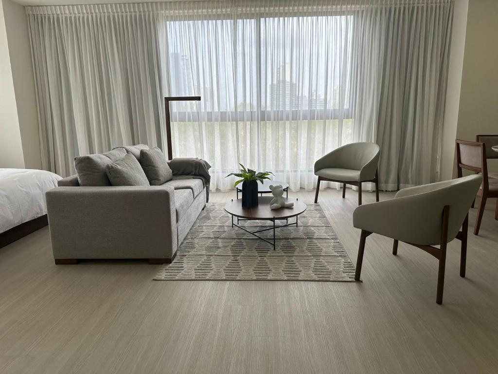 ein Wohnzimmer mit einem Sofa und einem Stuhl vor einem Fenster in der Unterkunft Arcadia Condo Suites in Panama-Stadt
