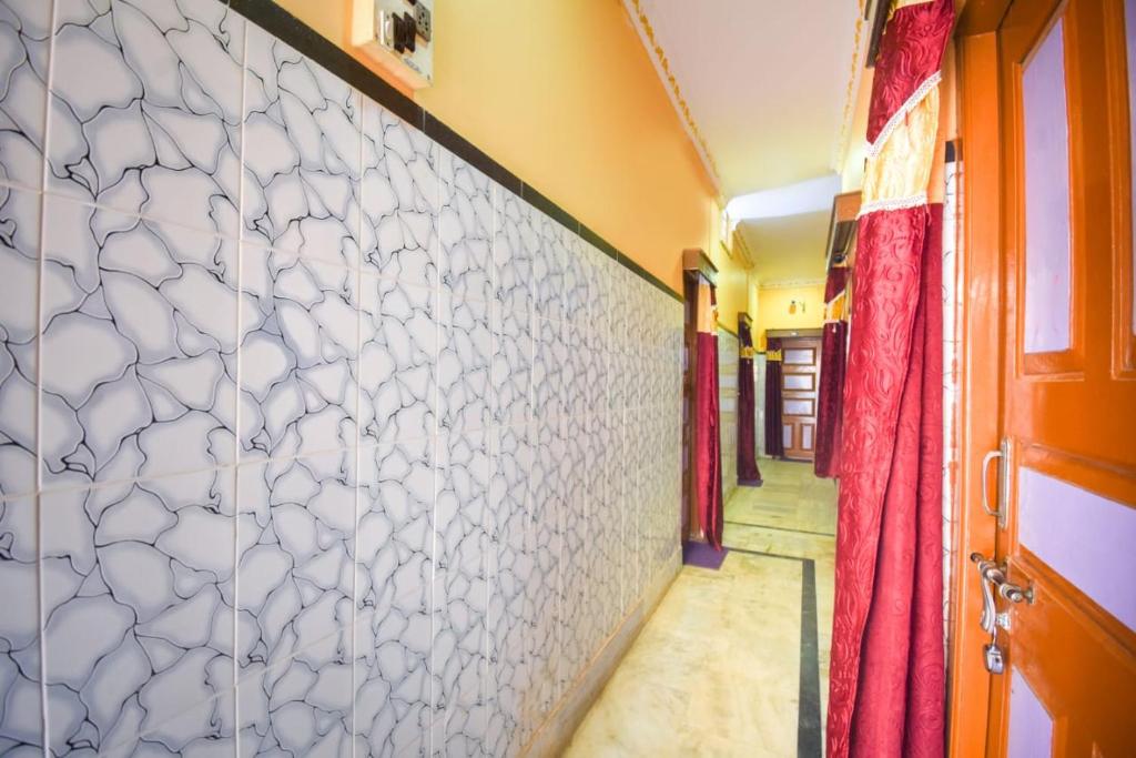 a hallway with a white tile wall and a red door at Anirudha Guest House in Digha