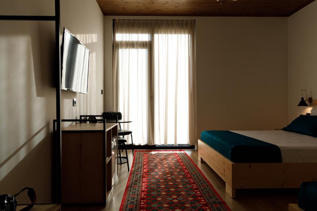 a bedroom with a bed and a tv and a window at The Barrels Ms in Gjirokastër