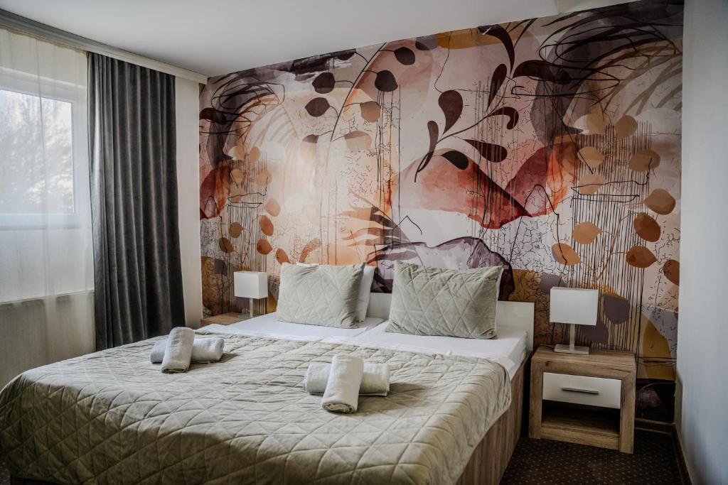 1 dormitorio con 1 cama grande y pared de flores en Plaza La - Night and Spa, en Sremska Mitrovica