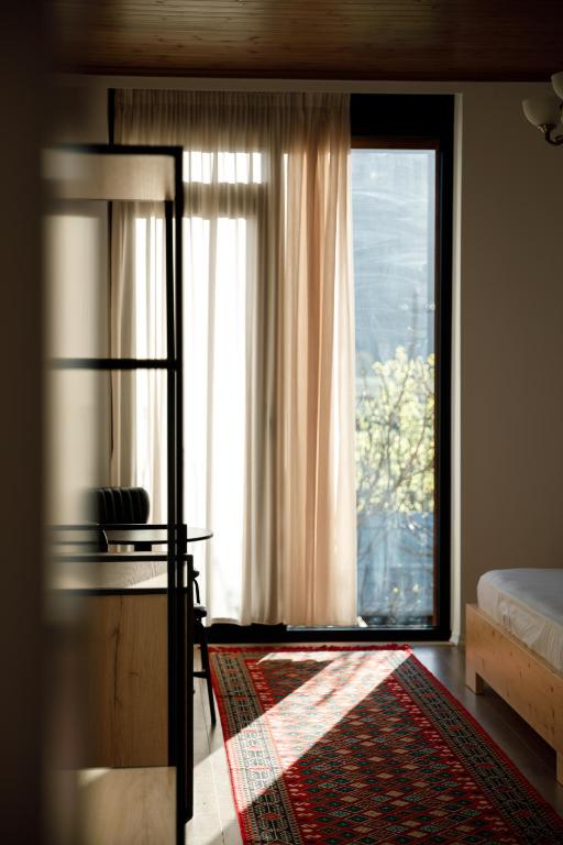 a bedroom with a window and a bed and a rug at The Barrels Ms in Gjirokastër