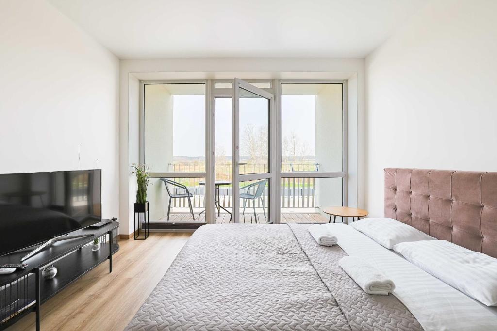 a bedroom with a large bed and a balcony at Studio W/Balcony @ManoŠventovė, By Cohost in Palanga