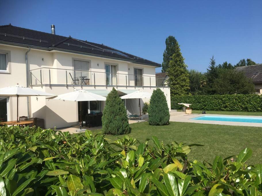 a house with a yard with a pool and umbrellas at Modern apartment easy commute, Geneva & Nyon 75m2 in Founex