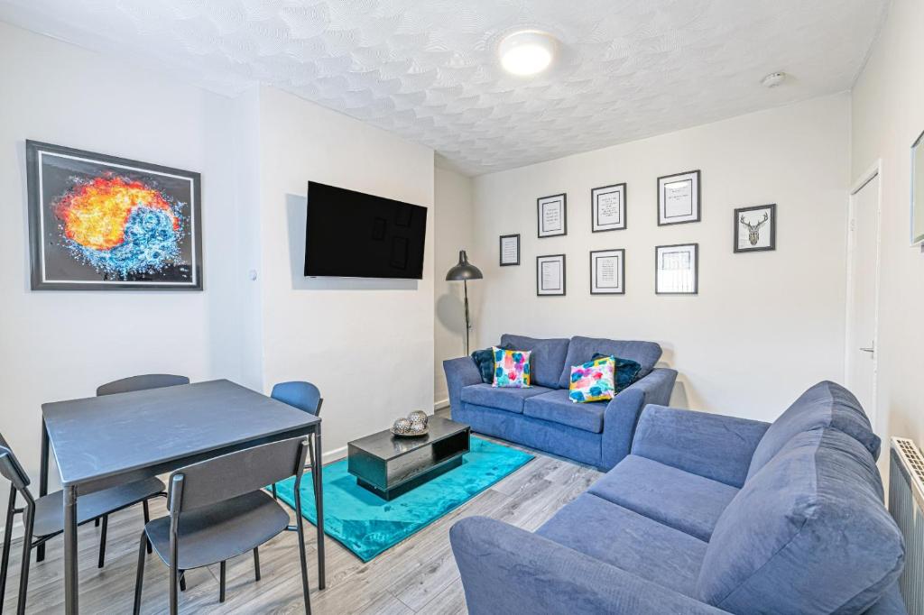 a living room with a blue couch and a table at Scott House - Contractor Friendly - Sleeps 7 in Liverpool
