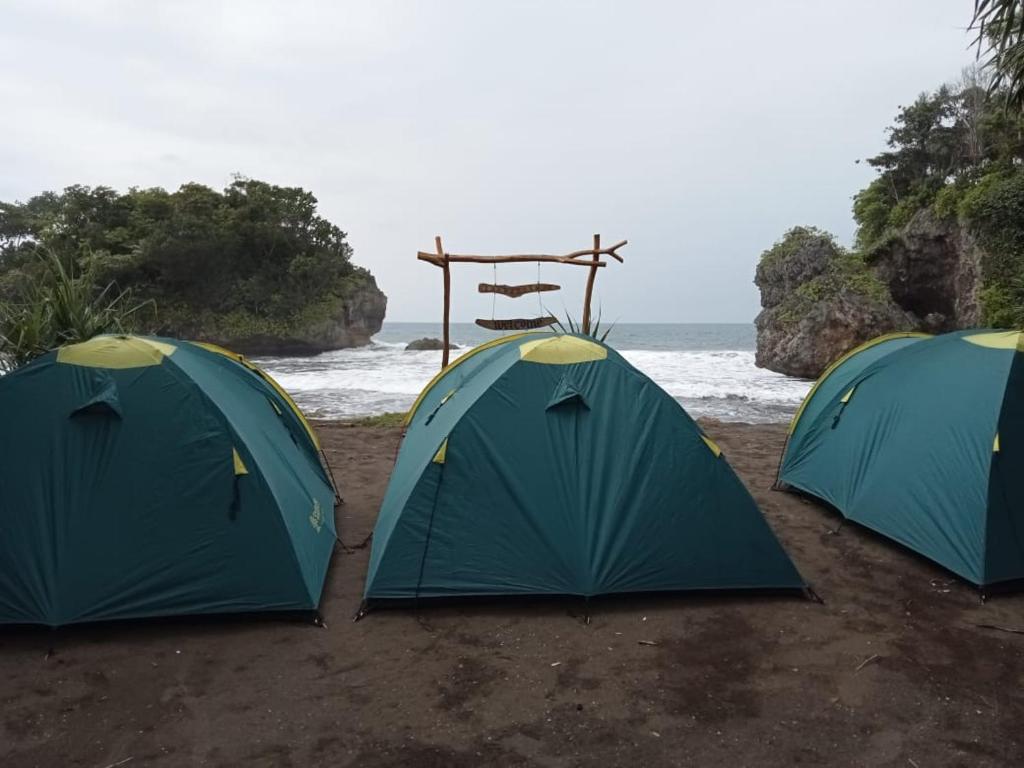 tres tiendas sentadas en una playa cerca del océano en Madasari Outdoor Camping Hemat en Bulakbenda
