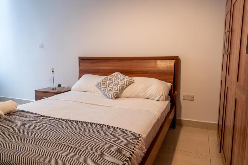 - un lit avec une tête de lit en bois dans une chambre dans l'établissement Cozy Bedroom, shared bathroom -Gzira, à Il-Gżira