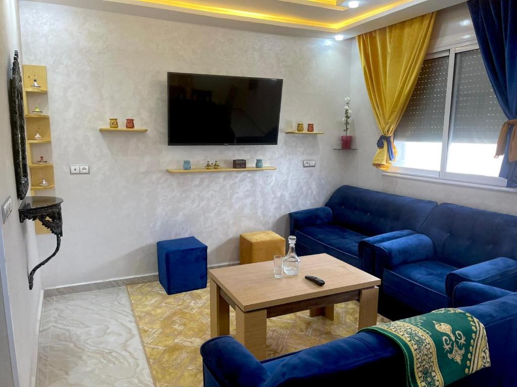 uma sala de estar com sofás azuis e uma televisão em Lagouira d'Agadir em Agadir