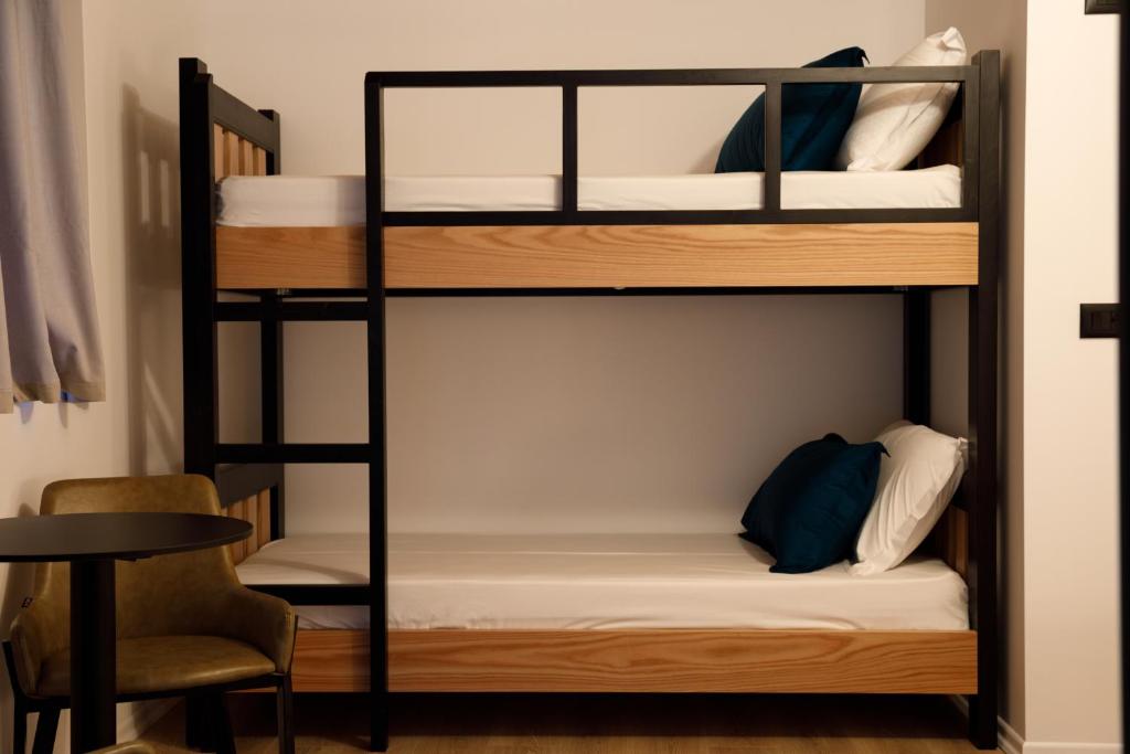 a bunk bed in a room with a table and a chair at The Barrels Ms in Gjirokastër