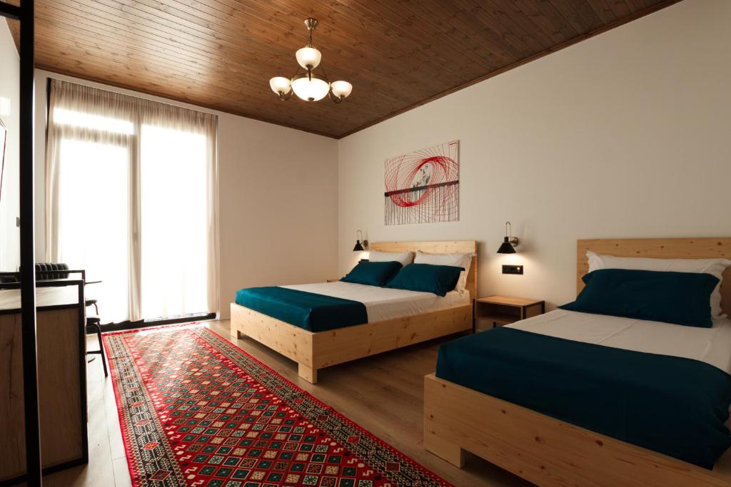 a bedroom with two beds and a rug at The Barrels Ms in Gjirokastër