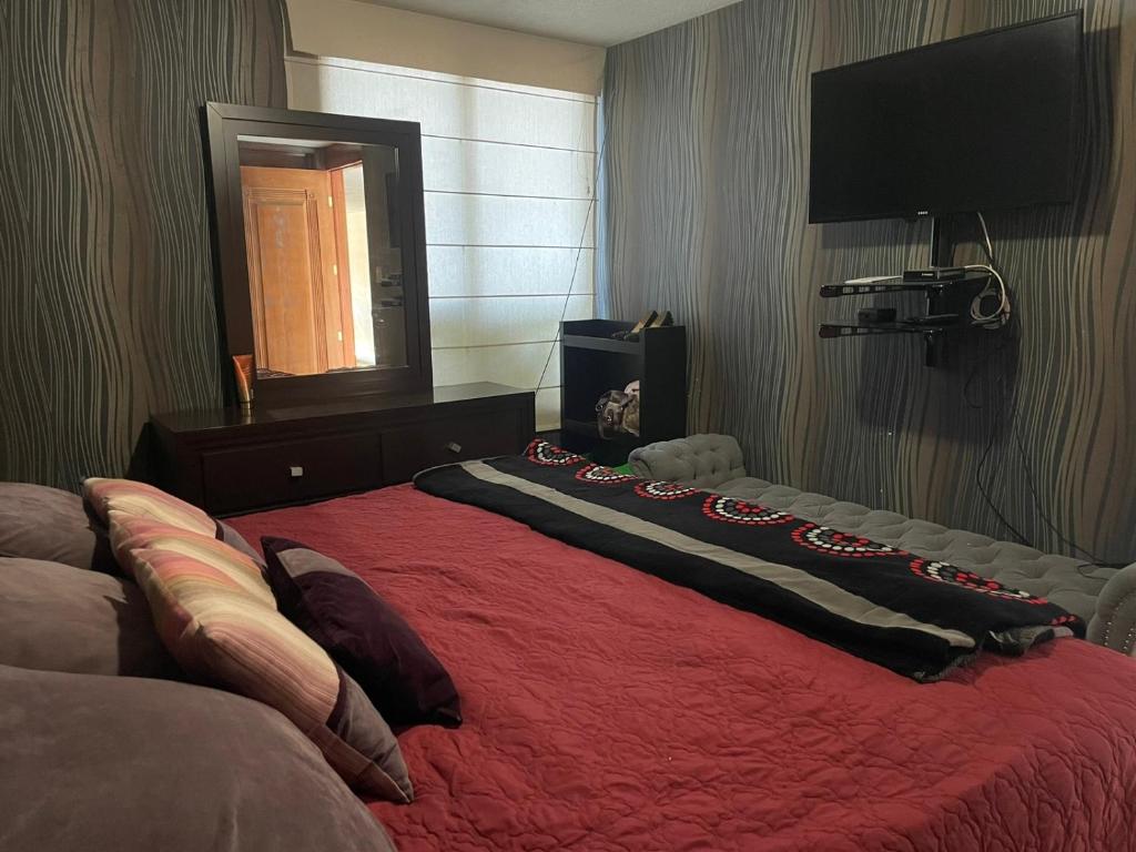 a bedroom with a bed with a red blanket at Habitación con baño propio in Mexico City