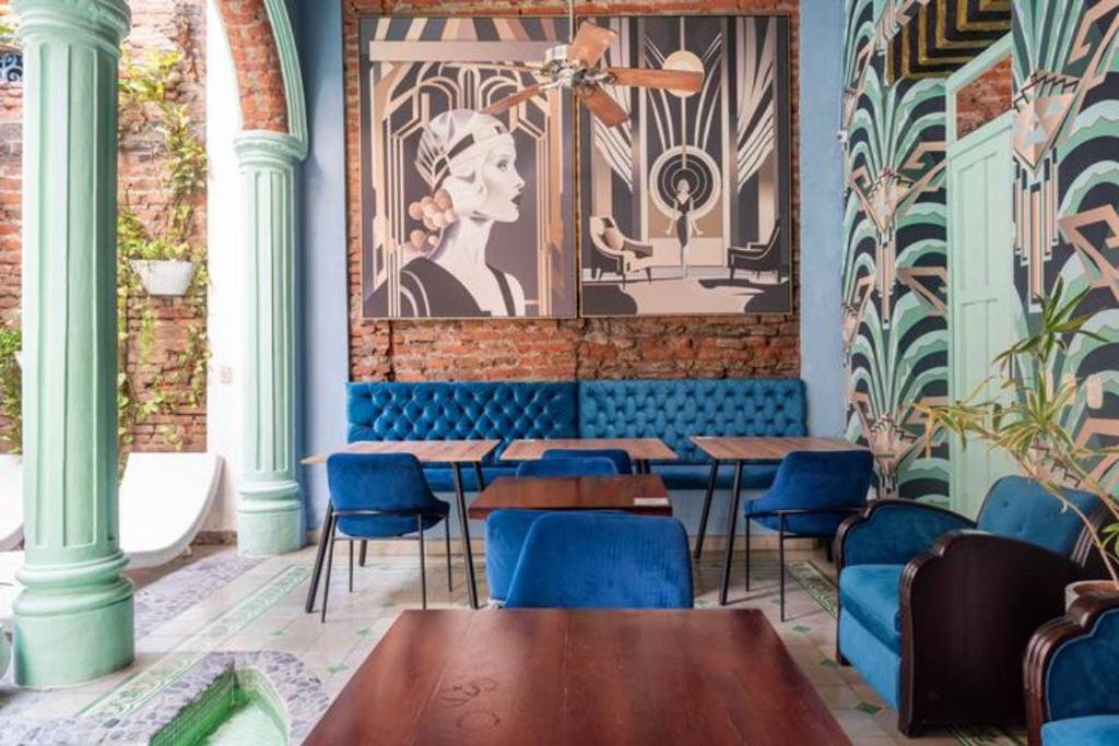 a restaurant with blue chairs and tables and a mural at Casa Verde Hotel in Santa Marta