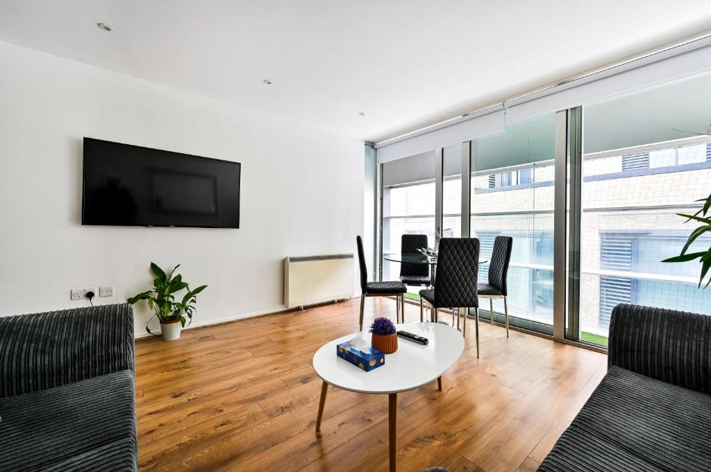 a living room with a table and chairs and a tv at That Cosy Stay - Fantastic 2 Bed Apartment - Stratford in London