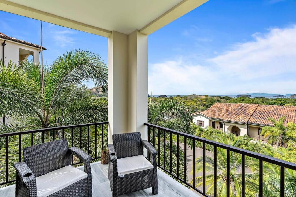 uma varanda com duas cadeiras e vista para uma casa em 3-Bedroom 3rd-Floor Ocean-View Condo em Coco