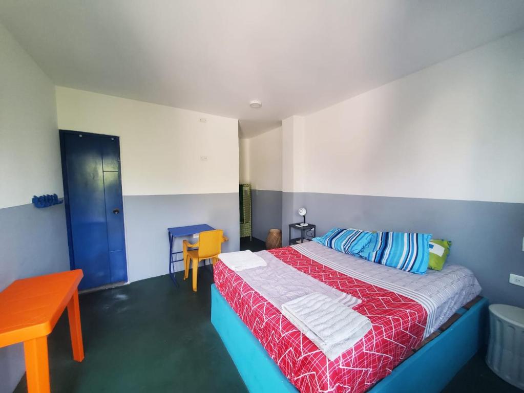 Hotelito La Aventura, private rooms with AC في كارتاهينا دي اندياس: غرفة نوم بسرير وبطانية حمراء وزرقاء