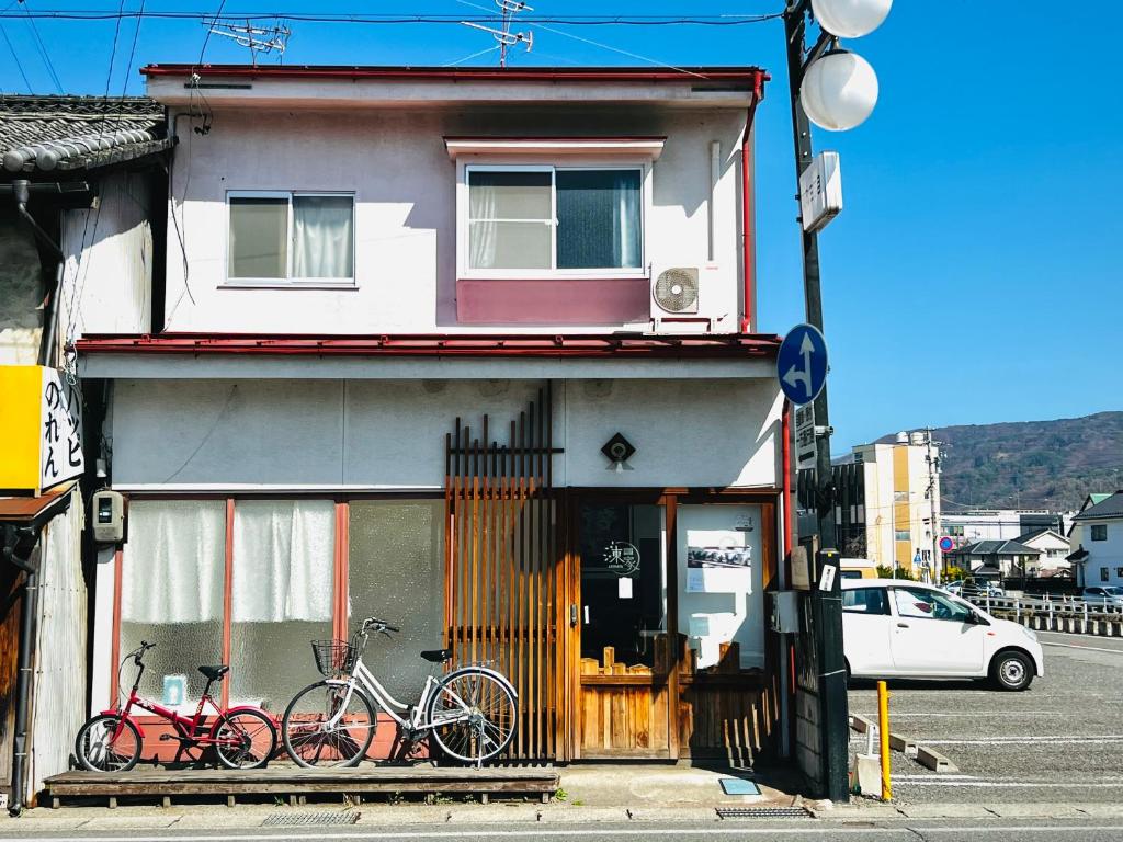 dos bicicletas estacionadas frente a un edificio en Guesthouse Azumaya en Matsumoto