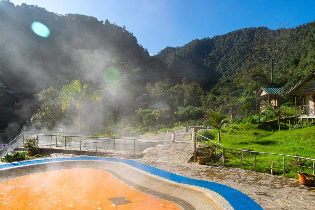 a hot spring with a bridge and mountains in the background at Hotel Termales San Vicente in Santa Rosa de Cabal