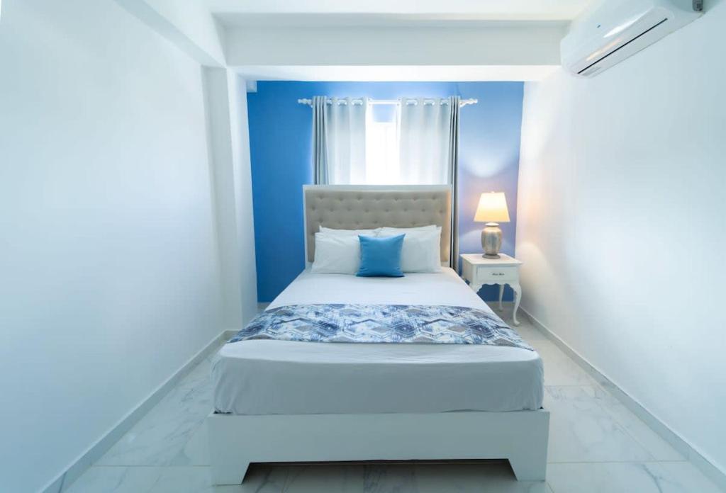 - une chambre avec un lit blanc et un mur bleu dans l'établissement Captivating 2-1 with Ocean Views, à Las Flores
