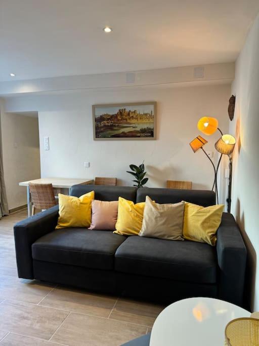 un salon avec un canapé noir avec des coussins jaunes dans l'établissement Appartement de plain-pied avec jardin, à Avignon