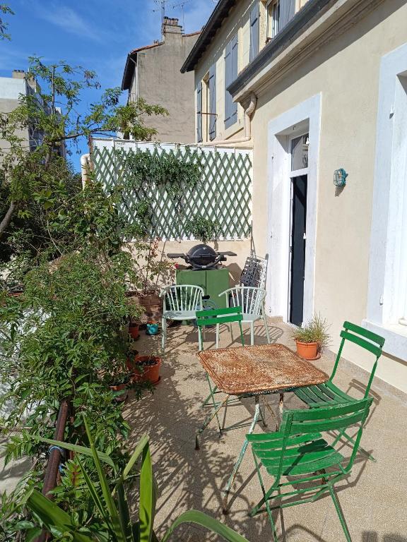 a patio with green chairs and a table and a fence at Chambre d&#39;hôte 1 pers - Maison avec terrasse et jardin près de la Friche de la Belle de Mai in Marseille