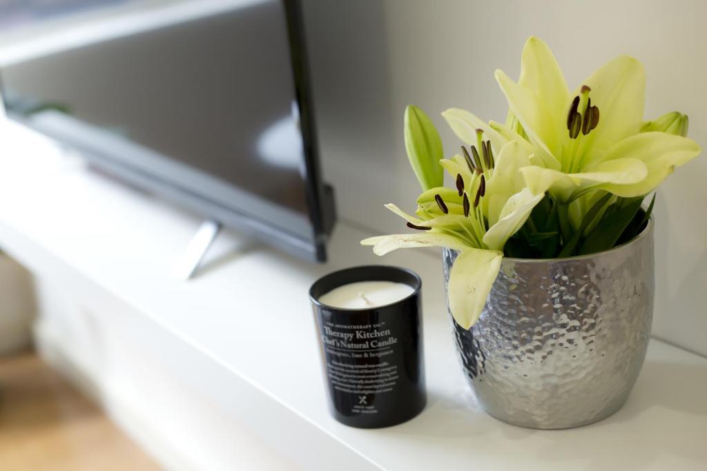 a vase of flowers on a desk with a candle at The Town Apartments in Melbourne