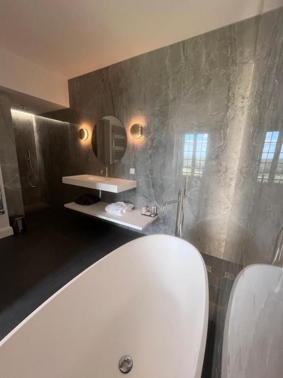 La salle de bains est pourvue d'une baignoire blanche et d'un lavabo. dans l'établissement L'Esplanade, à Domme