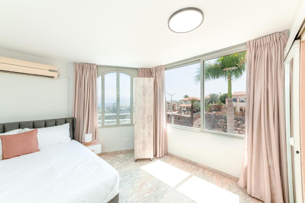 a bedroom with a bed and large windows at Villa Li Eilat in Eilat