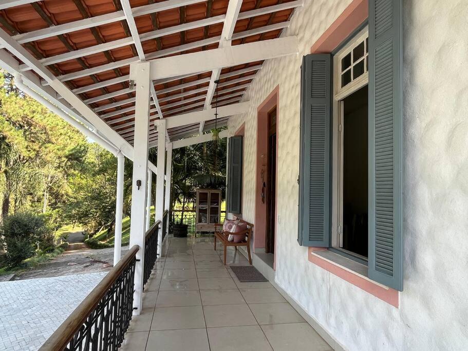 une terrasse couverte d'une maison avec un auvent et une chaise dans l'établissement Natureza. Condominio 50m de SP, à Itapecerica da Serra