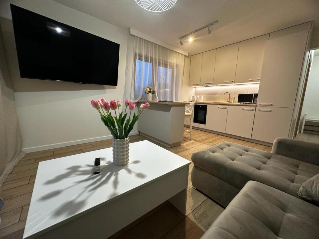 ein Wohnzimmer mit einem Sofa und einem Tisch mit Blumen darauf in der Unterkunft Apartamenty Biała Grań in Zakopane