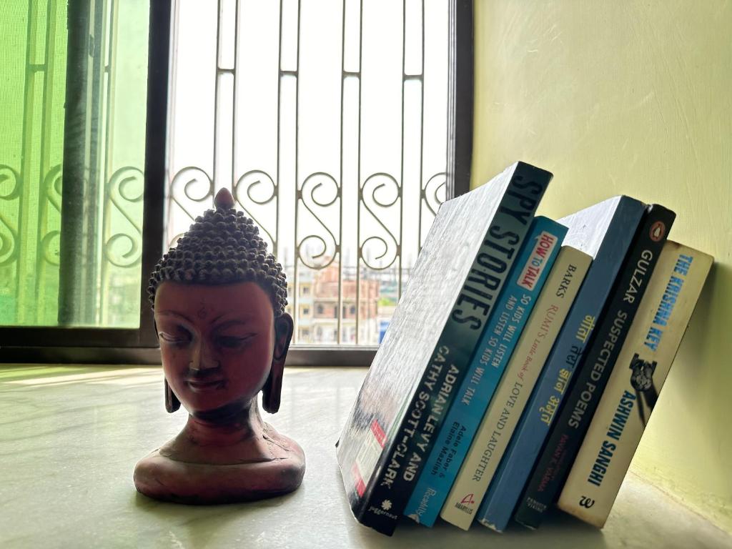 Amma’s Om stay في باتنا: مجموعة من الكتب تجلس على طاولة مع تمثال