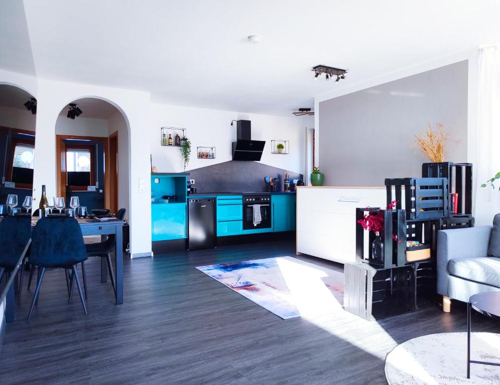 uma cozinha com armários azuis e uma sala de estar em Terminal Design Apartment - Terrasse & waipuTV em Steinenbronn