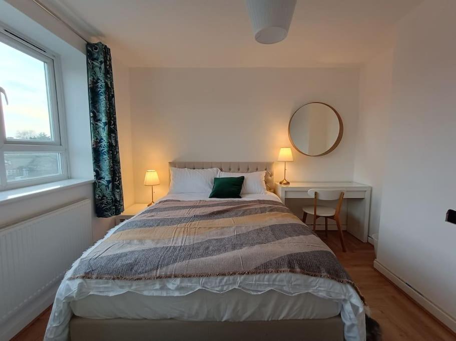 um quarto com uma cama, uma secretária e um espelho em Spacious 3 bed flat opp Springfield park, Hackney. em Londres