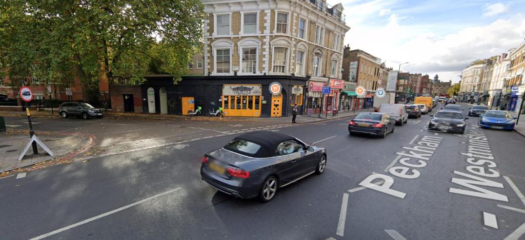 een straat met auto's die door een straat rijden bij Wood studio flat in Londen