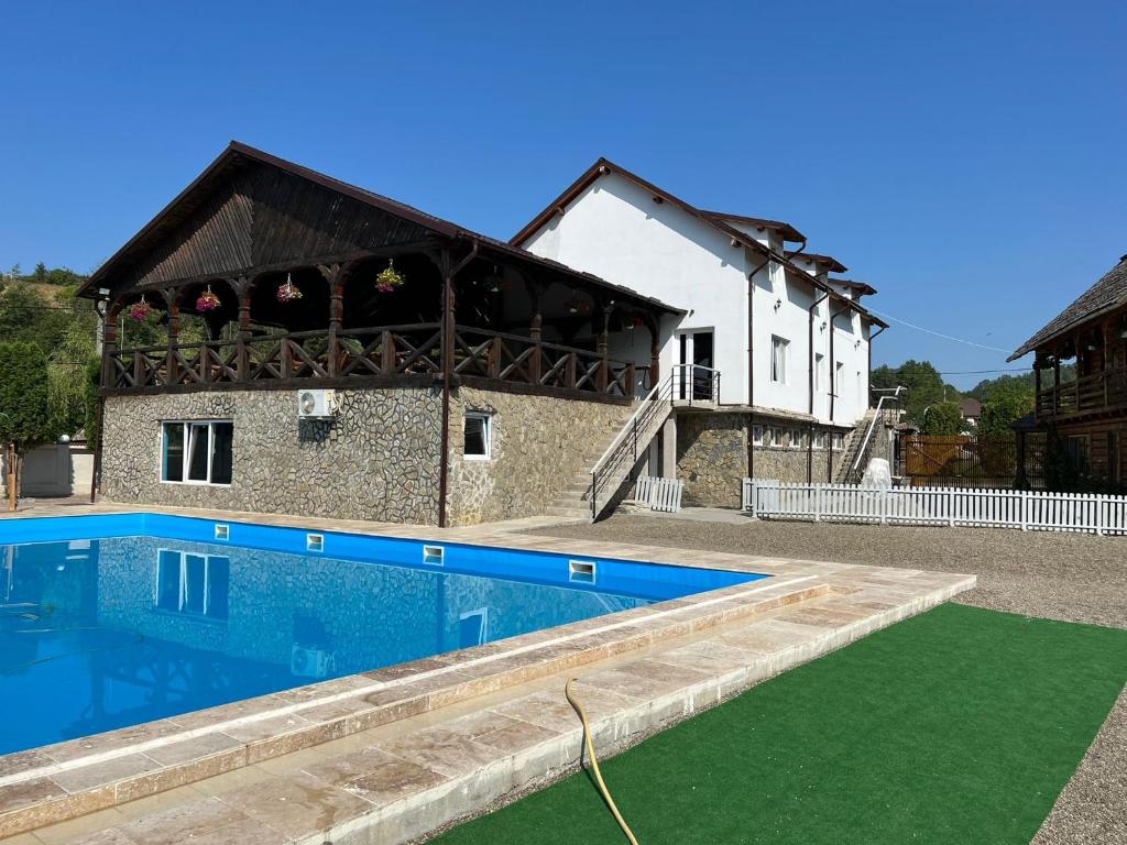 a house with a swimming pool in front of it at Pensiunea Mara Băile Botiza in Botiza