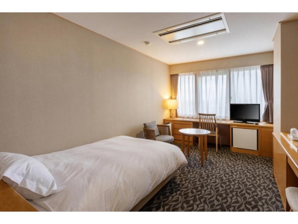 a hotel room with a bed and a desk and a television at Suikoyen Hotel - Vacation STAY 46436v in Kurume