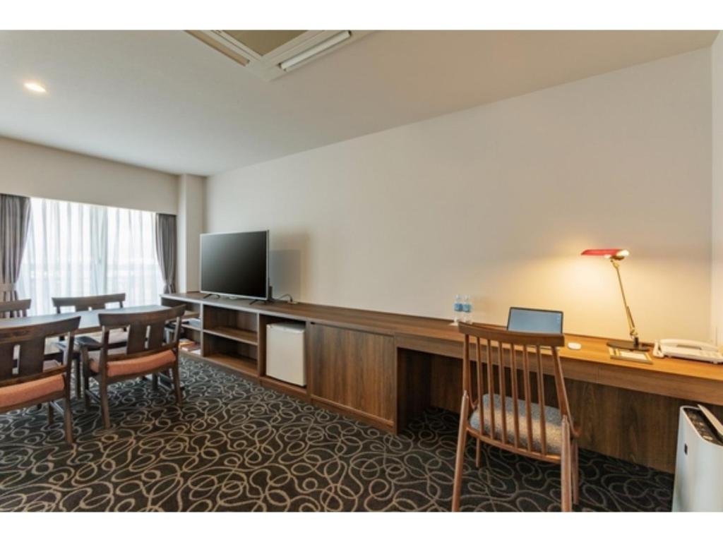 um quarto com uma secretária, uma televisão e uma mesa em Suikoyen Hotel - Vacation STAY 46475v em Kurume