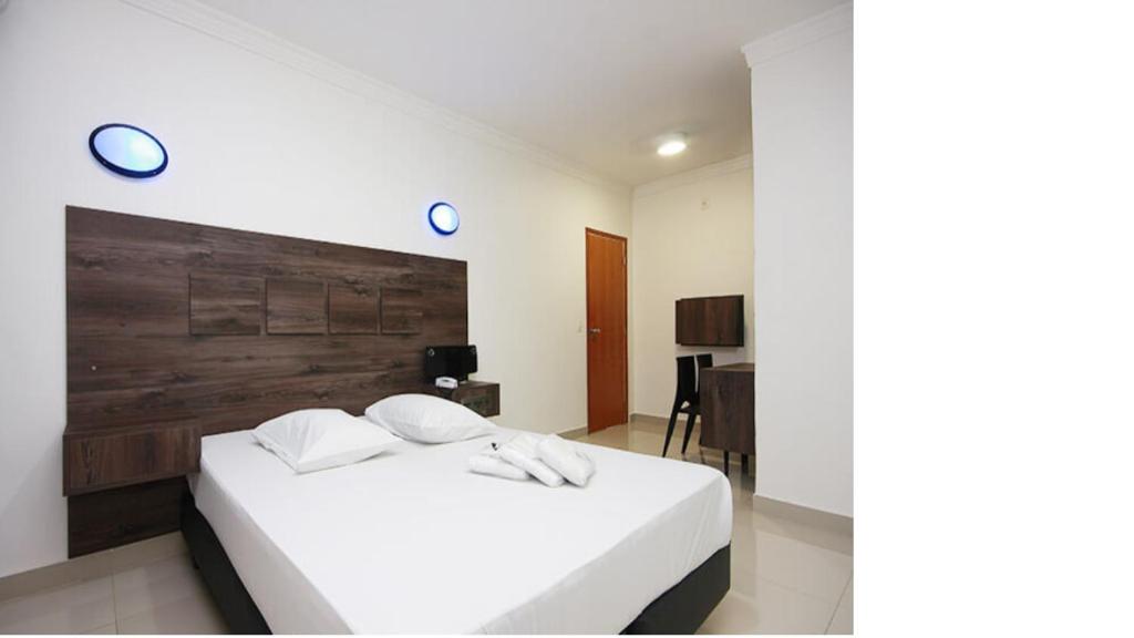 a bedroom with a white bed with a wooden headboard at Minuty Motel Itu in Itu
